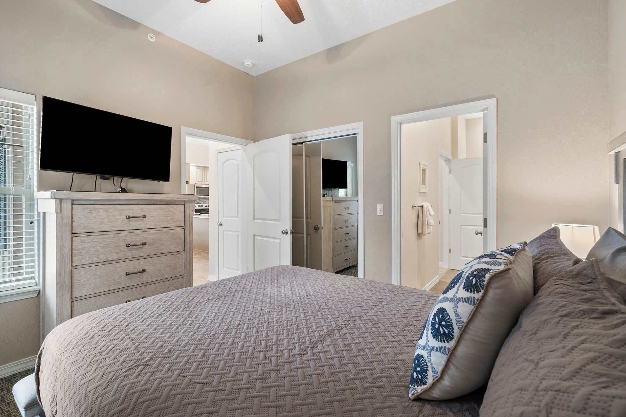 Un dormitorio con cama, cómoda, televisor y armario abierto.