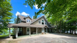 A two-story house with a covered porch, a satellite dish, and a view of a lake. - Panorama Cottage - perfect sunsets! (Parry Sound)
