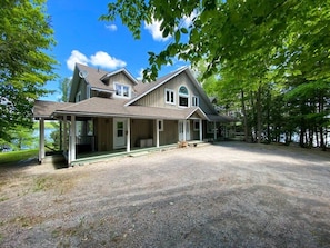 A two-story house with a covered porch, a satellite dish, and a view of a lake. - Panorama Cottage - perfect sunsets! (Parry Sound)