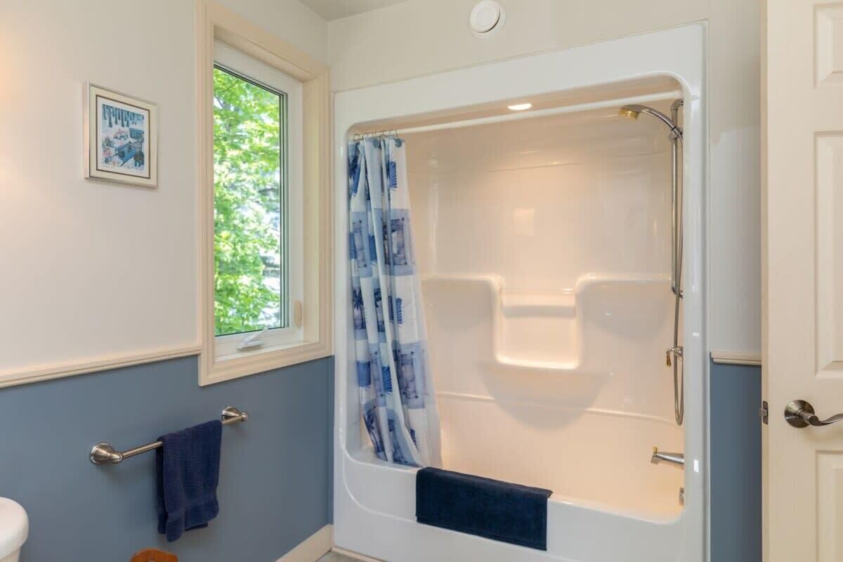 A bathroom with a bathtub, a window, and a towel rack.