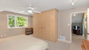 A bedroom with a bed, wardrobe, ceiling fan, and a window. - Panorama Cottage - perfect sunsets! (Parry Sound)