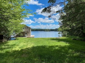 Une maison avec un quai s’avançant dans un lac, entourée d’une végétation luxuriante.