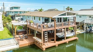 Una casa frente al agua con terraza, mobiliario exterior y un muelle para barcos.
