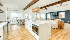 Una cocina moderna con una isla grande, vigas de madera y un comedor con vistas.