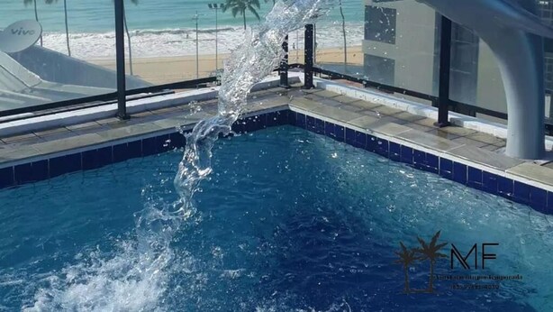 A dolphin-shaped water feature in a pool with a beach view. - AMETISTA (Maceió)