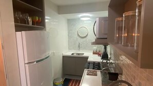 A compact kitchen with a refrigerator, sink, and a small countertop. - AMETISTA (Maceió)