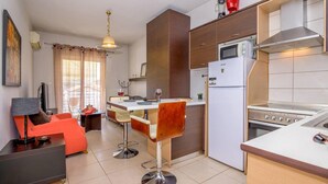 Una cocina compacta con comedor, refrigerador, estufa y un taburete de bar.