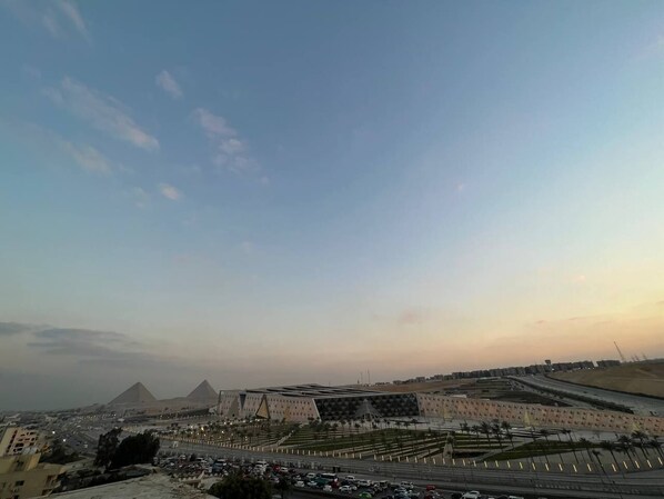 A cityscape with a large pyramid structure and modern buildings. - Asia Grand Museum & Pyramids View (Giza)