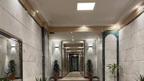 A spacious lobby with marble flooring, a central staircase, and potted plants. - Asia Grand Museum & Pyramids View (Giza)