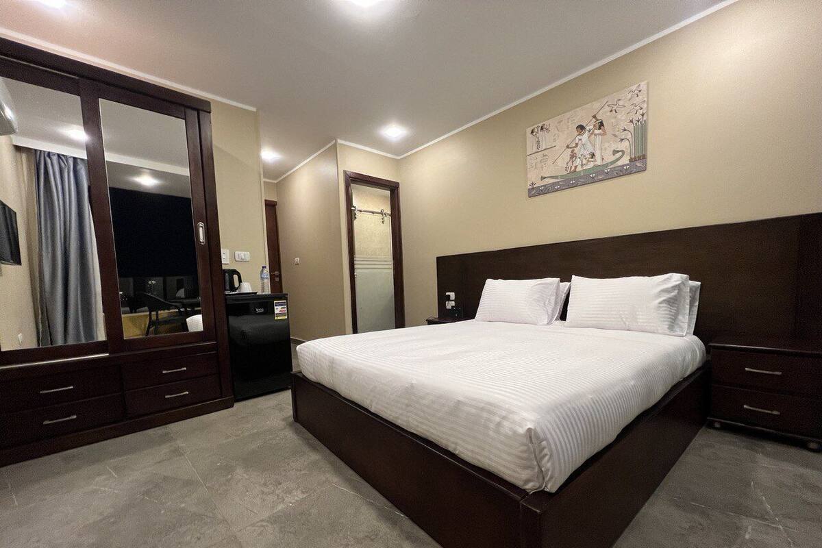 Una habitación de hotel con una cama grande, un armario, un escritorio y un espejo.