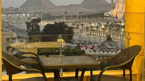 A view from a balcony overlooking the pyramids, with a street and modern buildings in the foreground. - Asia Grand Museum & Pyramids View (Giza)