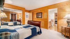 Een slaapkamer met twee bedden, houten wanden, een grote spiegel en een deur naar een badkamer.