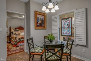 Cozy dining area with a round table and four chairs, complete with a chandelier and framed artworks.