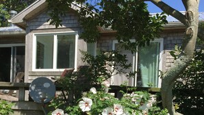 A house with a garden featuring white flowers and a wooden deck.