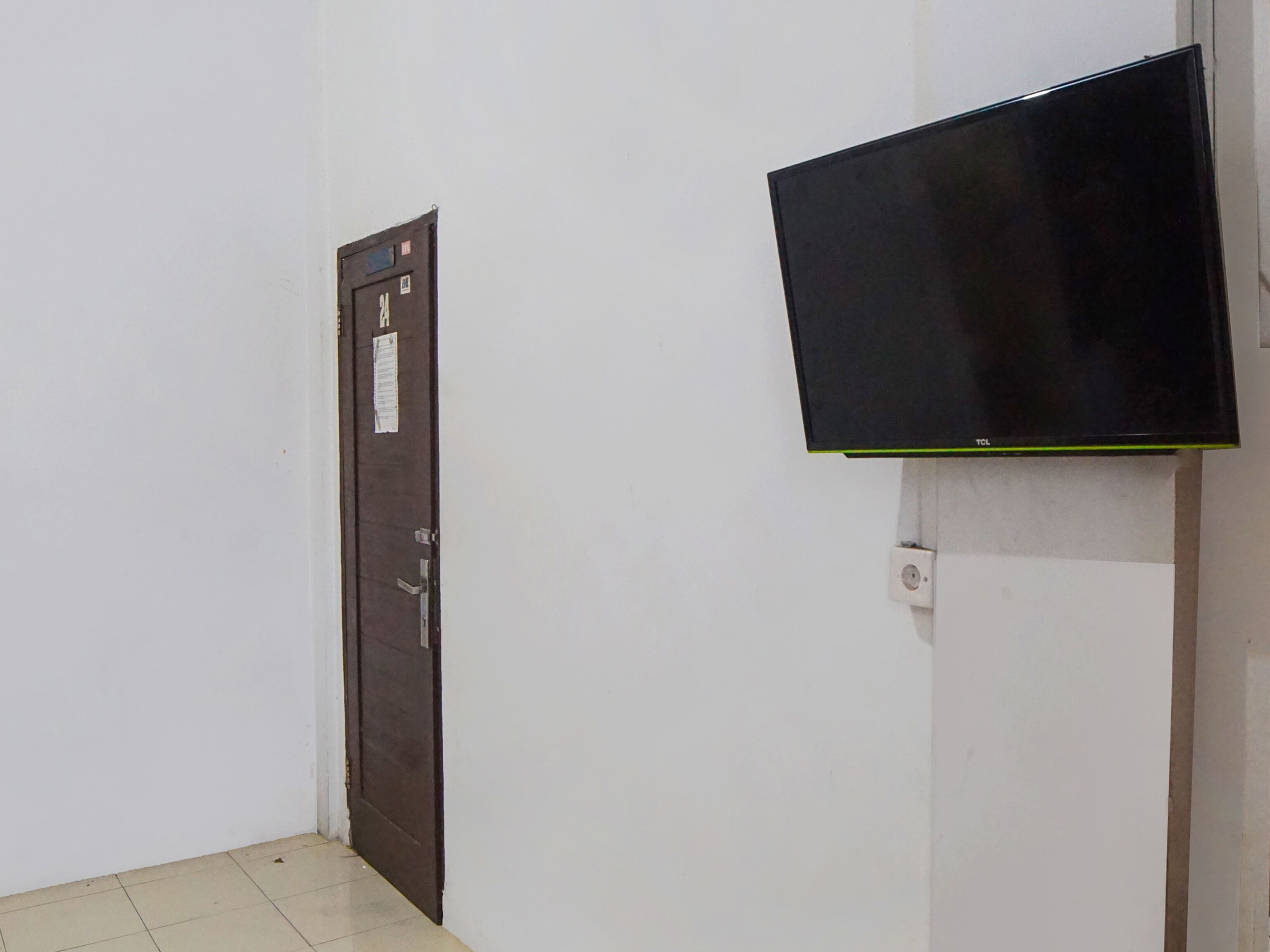 A room with a closed door and a mounted television on a stand.