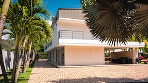 Een modern gebouw met twee verdiepingen en een plat dak, een met baksteen bestraate looppad naar de ingang en een klein buitenterrein met een barbecue.