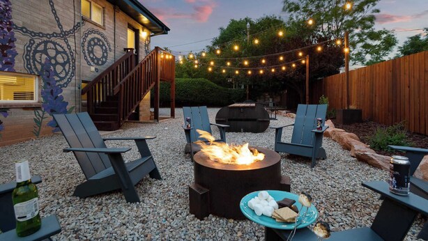 An outdoor patio with a fire pit, seating, and string lights.