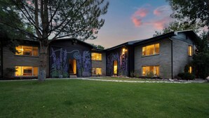 A modern two-story house with a well-maintained lawn, large windows, and decorative wall art.