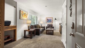 A living room with a sofa, two side tables, a coffee table, and a door with a keypad lock.