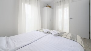 Ein sauberes, modernes Hotelzimmer mit einem ordentlich bezogenen Bett, einem Kleiderschrank und einer Tür.