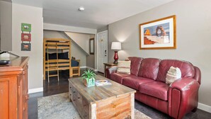 Ein Wohnzimmer mit einem roten Ledersofa, einem Holztisch und einer Treppe, die zu einer anderen Ebene führt.