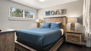 Ein Schlafzimmer mit einem Bett, zwei Nachttischen, einem Fenster und einem an der Wand befestigten Schild.