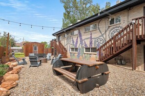 Eine Terrasse mit Holztisch, Stühlen und einem dekorativen Wandgemälde.