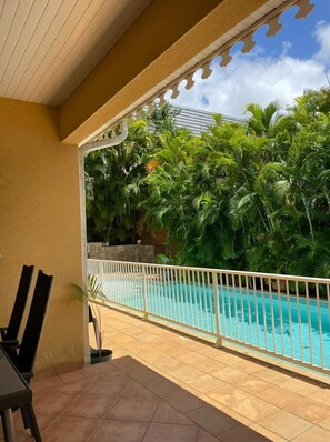 Relax by the pool surrounded by lush greenery and a beautiful pergola.