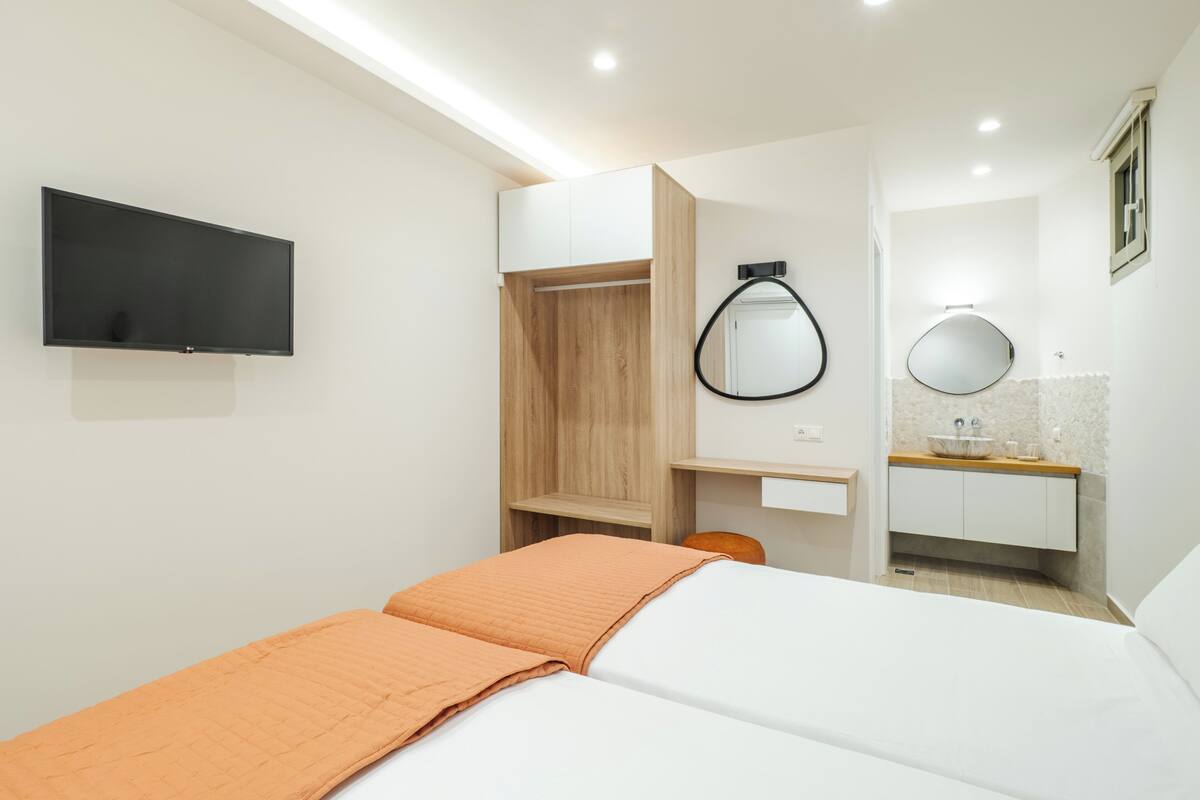 Ein Hotelzimmer mit Bett, Fernseher, Spiegel, Waschbecken und einem Holzschrank.