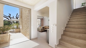 Un interno spazioso con una scala moderna, un'area pranzo e vista sull'esterno.