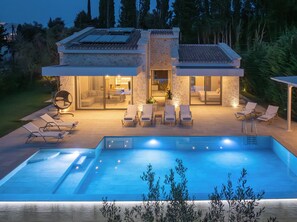 A modern house with a swimming pool, outdoor seating, and a stone facade. - My Mediterranean Villa in Corfu (Corfu)
