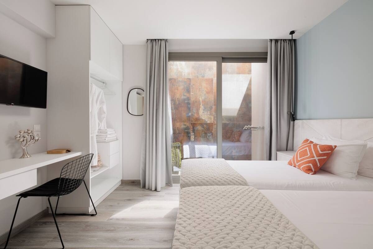 Ein modernes Hotelzimmer mit Bett, Schreibtisch, Stuhl, Fernseher und Blick auf die Stadt.