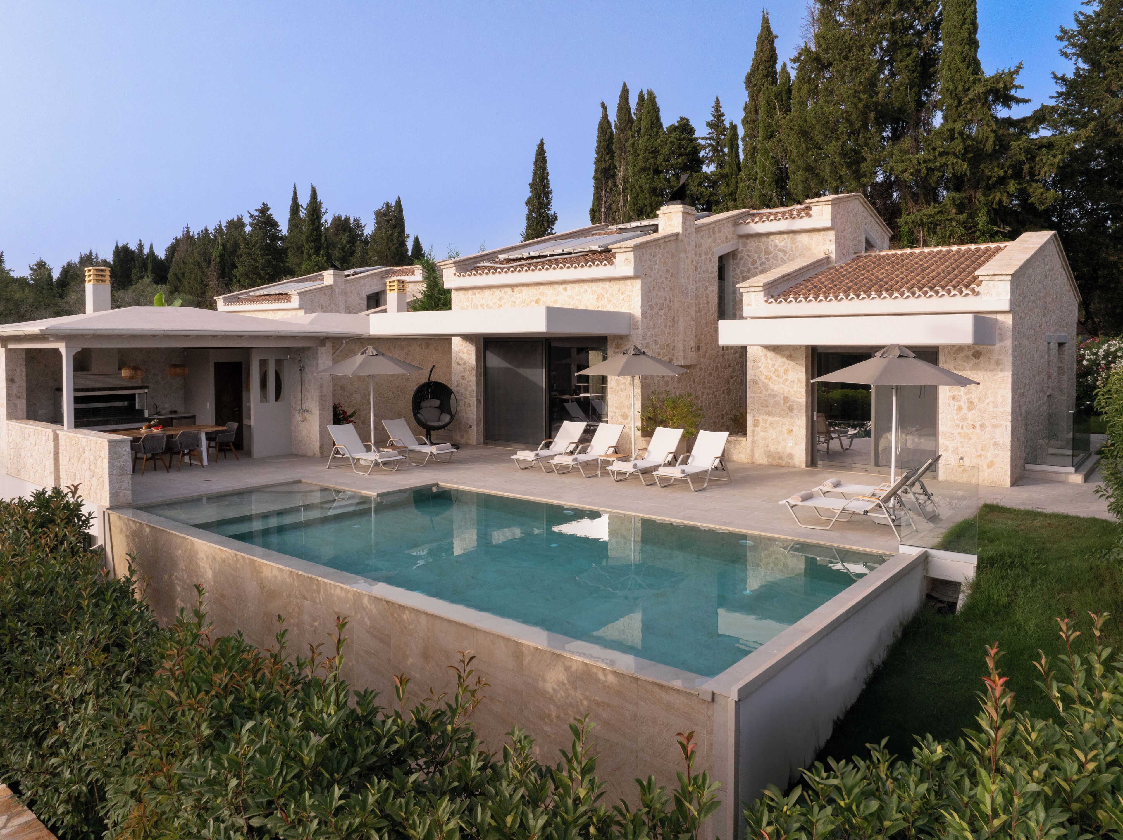 Une maison moderne dotée d’une piscine, d’un espace salon extérieur et d’un jardin.