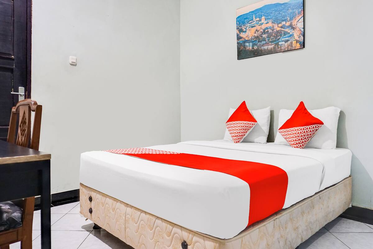Ein Hotelzimmer mit Bett, einem Bild an der Wand und einem Essbereich mit Stühlen.