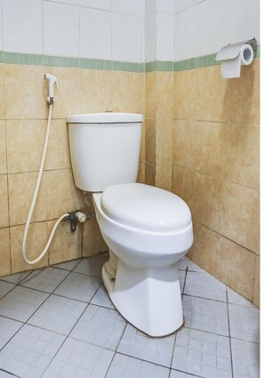 Inodoro blanco con asiento bidé en un baño con baldosas color beige y blanco.