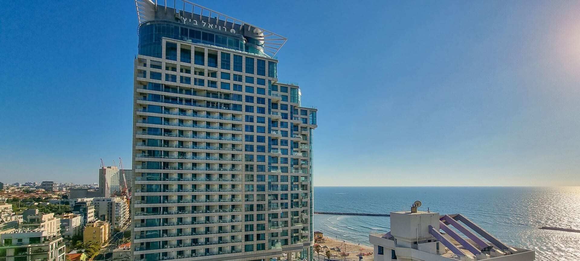 Un hotel moderno de gran altura, con múltiples balcones y vistas al mar.