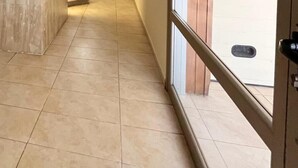 En hall med kakelgolv och en trädörr på vänster sida.