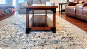 A living room with a wooden coffee table, a gray sofa, and a brown leather couch. There are wall decorations including a sailboat painting and nautical-themed items. - Paradise Vibes! 4-bedroom house in welcoming Bolivar Peninsula! (Bolivar Peninsula)