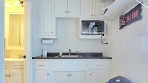 A kitchen with white cabinets, a microwave, a sink, and a trash bin. - Paradise Vibes! 4-bedroom house in welcoming Bolivar Peninsula! (Bolivar Peninsula)