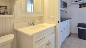 A bathroom with a white vanity, a sink, a mirror, and a toilet. There is a shelf with a blender and other kitchen items. - Paradise Vibes! 4-bedroom house in welcoming Bolivar Peninsula! (Bolivar Peninsula)