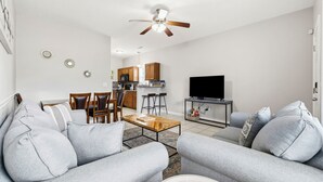 A living room with a sofa, coffee table, TV, and a ceiling fan. - 2 Bed, 2 Bath Coral Cottage—Walk to the Beach! (Myrtle Beach)