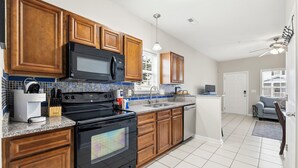 A modern kitchen with wooden cabinets, a black stove, a microwave, and a sink. - 2 Bed, 2 Bath Coral Cottage—Walk to the Beach! (Myrtle Beach)