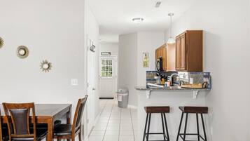 A kitchen with wooden cabinets, a countertop with a sink, and a dining area with a table and chairs.