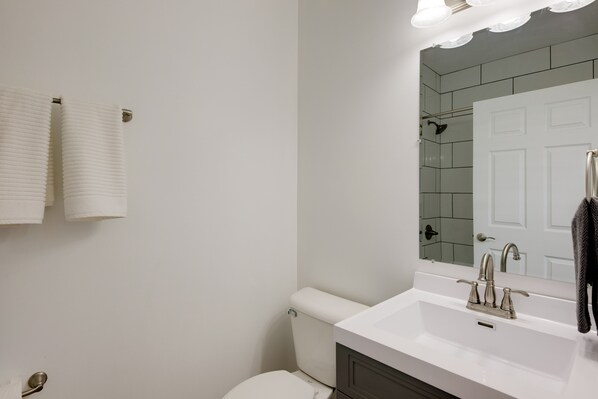 A bathroom with a white sink, a mirror, and a toilet.