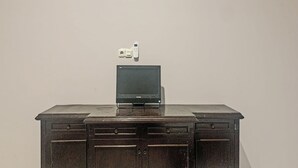 Uma mesa de madeira com uma televisão de tela plana e um dispositivo eletrônico branco em cima.