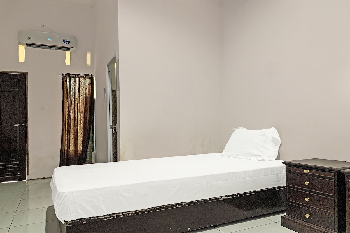 Ein Zimmer mit einem Bett, einem Schminktisch, einer Klimaanlage und einem Vorhang.