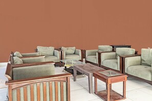 A living room with a sofa set, a coffee table, and a TV stand. - Hotel O Penginapan Radja Jeneponto (Jeneponto)