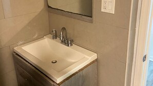 A bathroom with a white sink, a mirror above it, and a wooden cabinet below. - Eco-Shared Hype  (Miami)