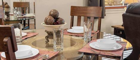 A dining area with a round glass table set for four, surrounded by wooden chairs.