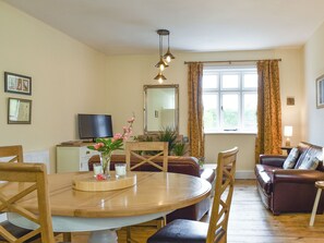 A dining area with a round table, chairs, a television, and a sofa.